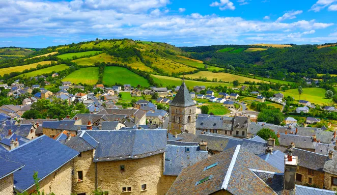 photo des toits de maisons d'un village avec vue sur une prairie de montagne au loin